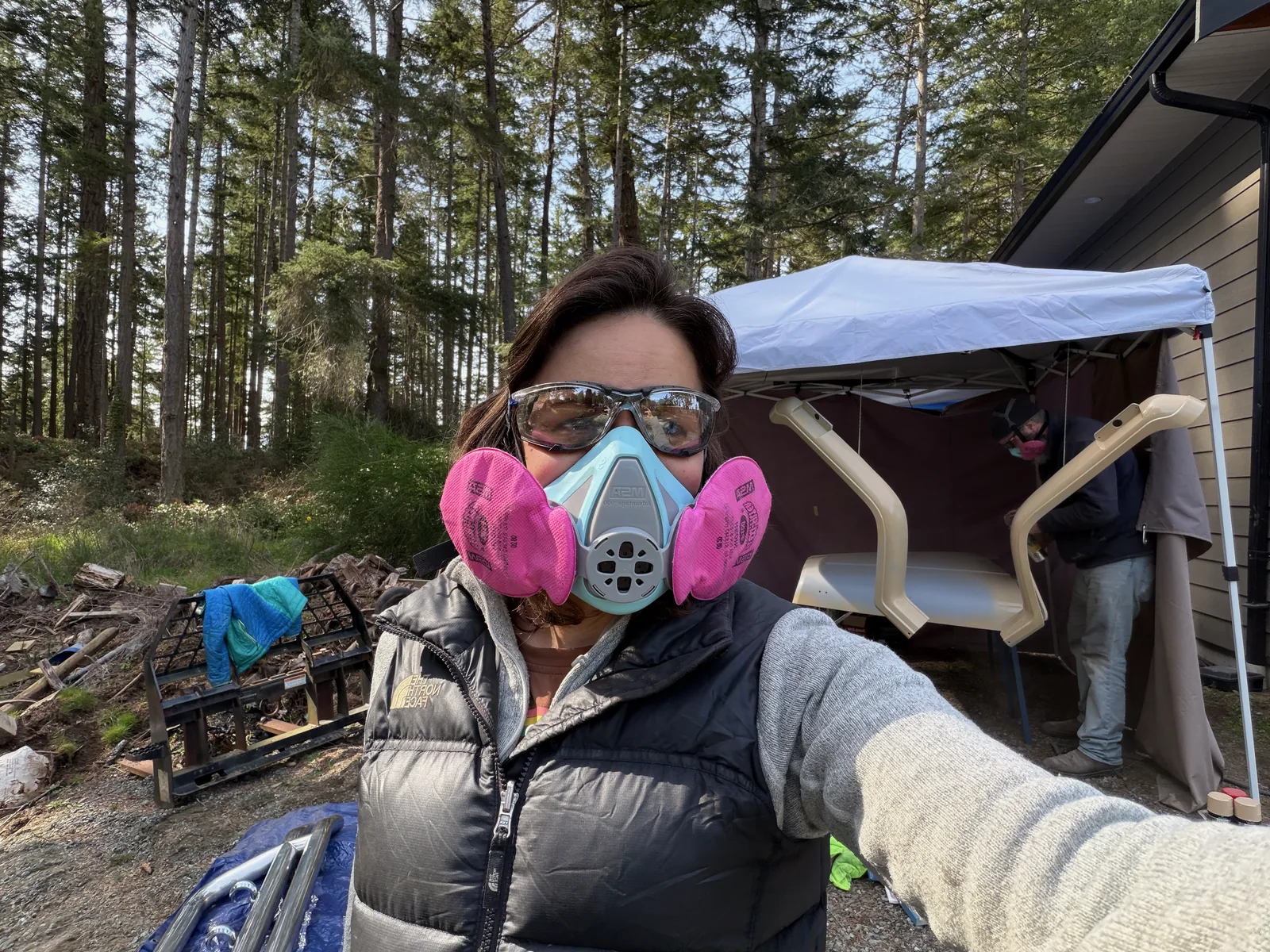Teryn in a respirator and safety glasses taking a selfie at the work site