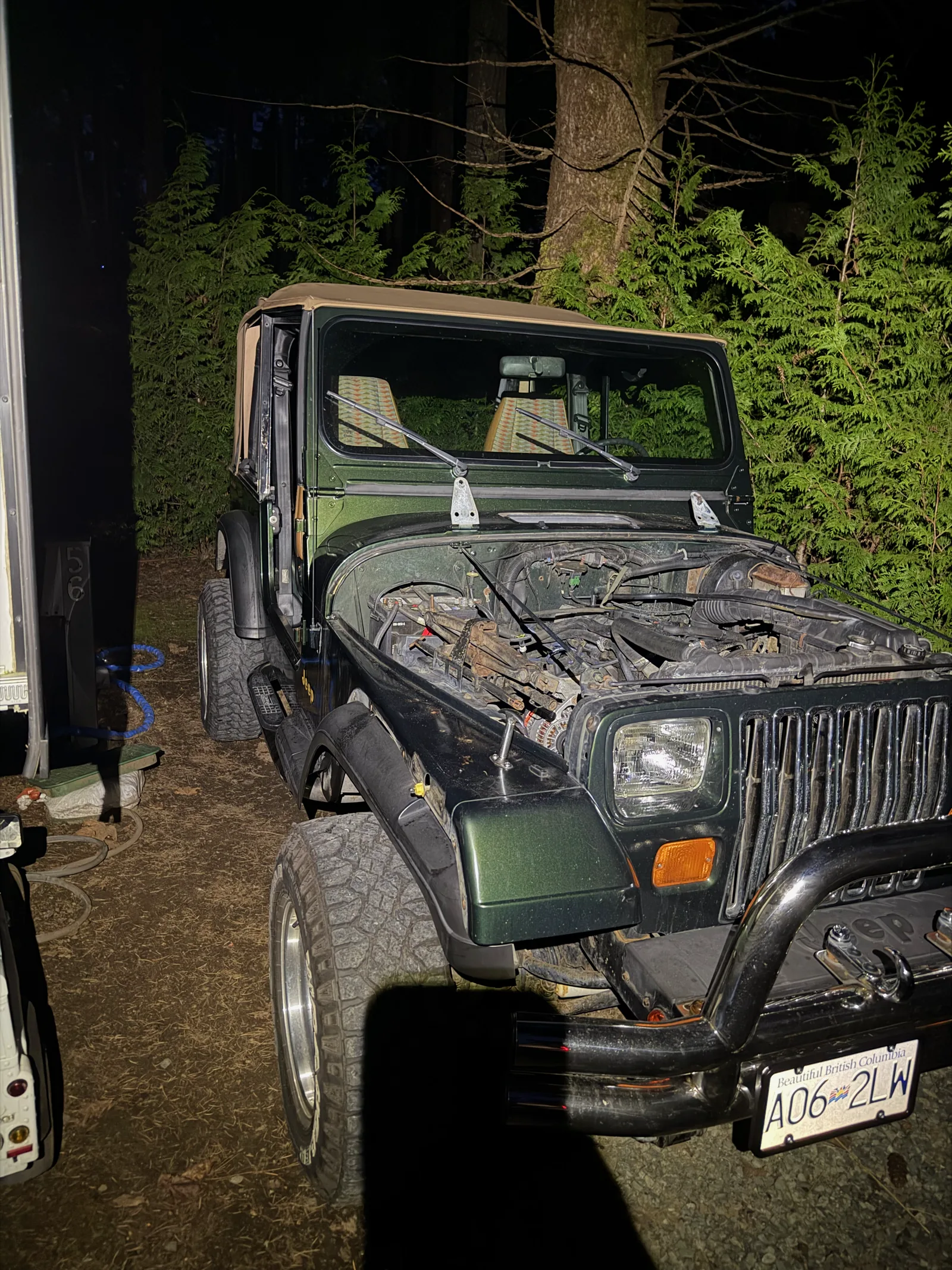 The rough metallic green Jeep at home in the driveway, ready to be worked on