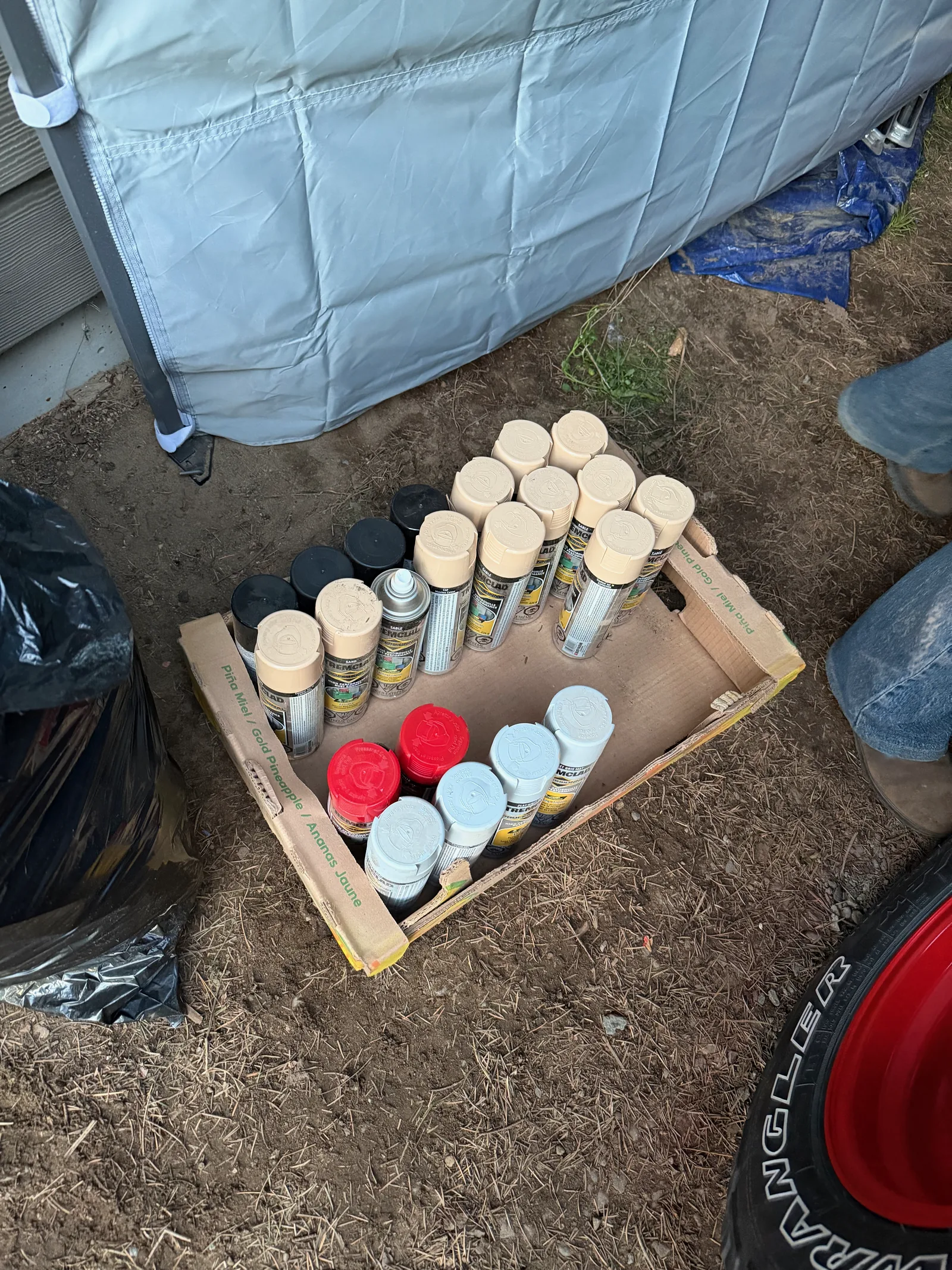 A crate full of empty tan spray paint cans