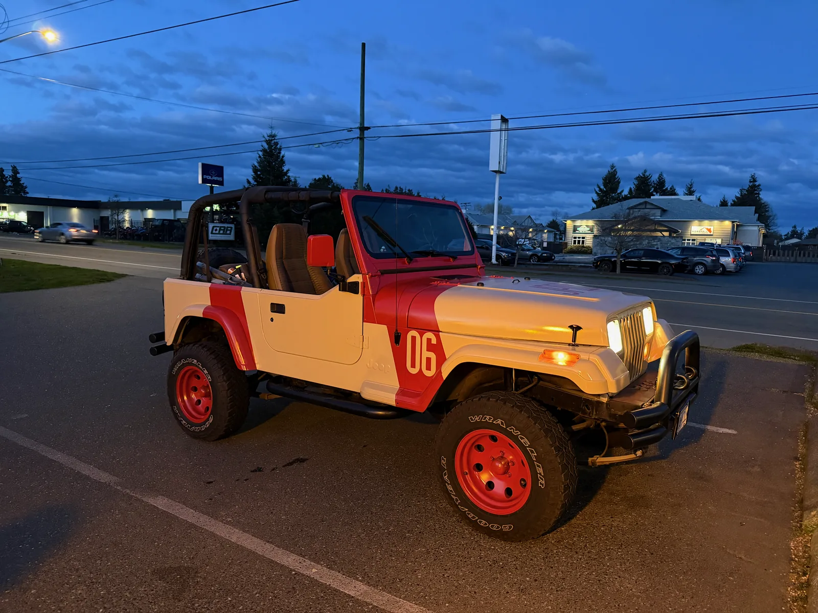 The finished Jeep on the road at dusk with its light bar and red wheels
